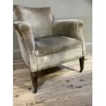 An Edwardian upholstered armchair on square tapered legs with casters