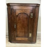 A 19th century oak hanging corner cupboard having a moulded cornice over an ogee indented panel