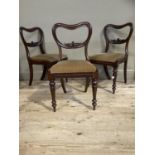 A set of three Victorian mahogany balloon back dining chairs with foliate carved back, upholstered