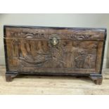 A camphorwood chest, the lid and panels carved in low relief with chinoiserie scenes