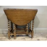 A small oak oval drop leaf gateleg table on barley twist and square framing