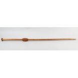 A HARDWOOD STAFF, having a T shaped head, the shaft carved with a serrated and flattened oblong,