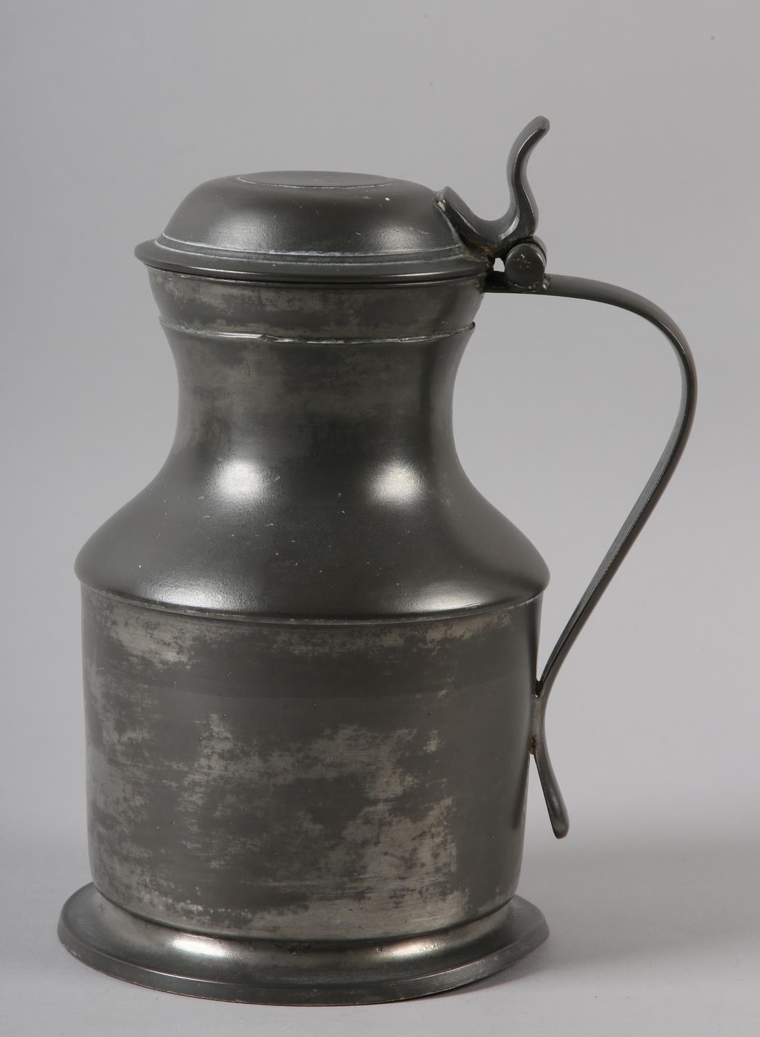 A LIDDED PEWTER FLAGON OF WAISTED FORM, the domed lid with thumb piece and a strap handle, the