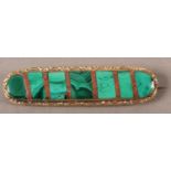 A VICTORIAN MALACHITE BROOCH, collet set within an elongated oval interspaced with strips of red