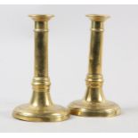 A PAIR OF 18TH CENTURY BRASS PRICKET CANDLESTICKS, the cannon columns on circular domed bases,