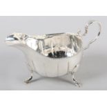 A GEORGE III IRISH SILVER SAUCE BOAT with a punchwork rim and flutes, scroll handle and on three