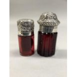 TWO VICTORIAN RUBY GLASS SCENT BOTTLES with silver repousse scroll hinged tops, Birmingham 1897