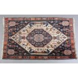 A MIDDLE EASTERN RUG, the ivory ground with indigo medallion filled with stylised plant forms,