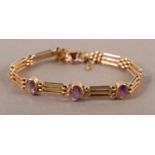 AN EDWARD VII AMETHYST SET GATE BRACELET in 9ct rose gold, the oval faceted stones collect set and