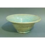 A studio pottery circular bowl, the raku glaze tinted from duck egg blue to turquoise, on circular
