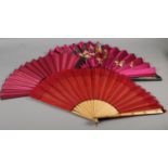 Three late 19th century fans, all with wood montures, with decorative gilding, the cerise silk leaf,