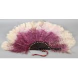 An ostrich feather fan, shaded from purple to lilac and ending in cream, the monture of