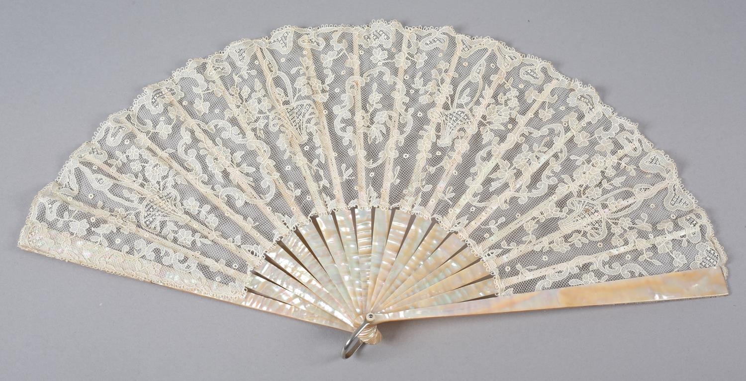 A folding fan c 1900 with pink mother of pearl monture, continuing onto the ribs, the lace leaf of a