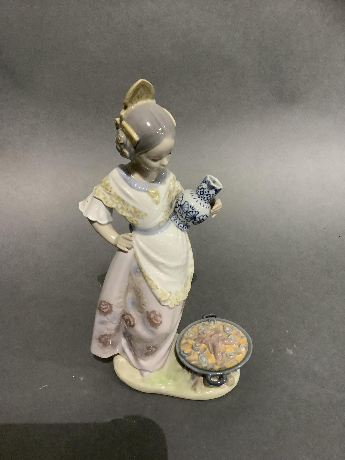 A Lladro figure of a Spanish girl holding a jug on her hip, a seafood paella cooking on a fire at - Image 2 of 4