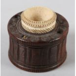 A late 18th/early 19th century treen inkwell, of drum shape carved with vertical bands and milled