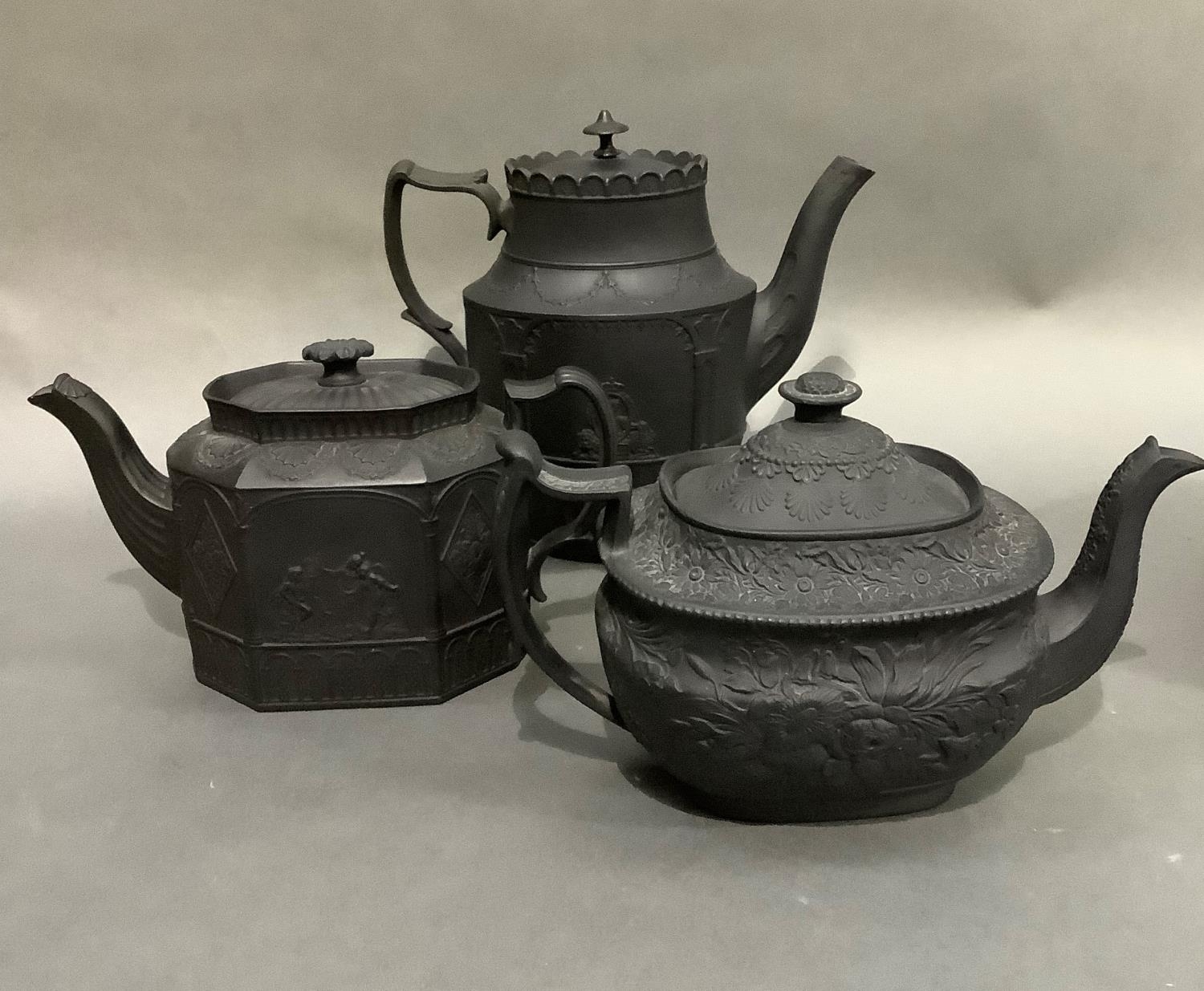 Three black basalt teapots, two of neo-classical design, oval and octagonal outline, the third
