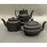 Three black basalt teapots, two of neo-classical design, oval and octagonal outline, the third