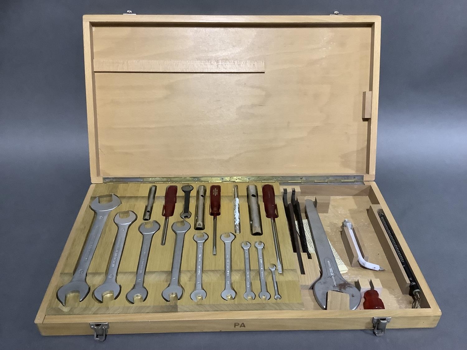 A German Saltus wooden tool case fitted with spanners in graduated sizes, screwdrivers, socket