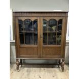 An oak and glazed two door bookcase having an arcaded frieze over three quarter glazed doors on