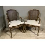 Two French style elbow chairs with bergère caned back and seat, (without cushions)