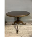 A circular stained pine breakfast table on pedestal and tripod base