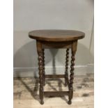 An oak circular occasional table on barley twist legs and square framing