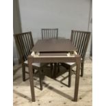 A modern rectangular extending dining table and three rail back chairs