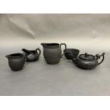 A Wedgwood black basalt sugar and cream and larger jug of the same design, the body moulded with