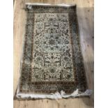A Persian style silk rug having an ivory ground, duck egg blue borders, all over scrolling foliate