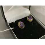 A pair of amethyst ear studs in 9ct gold, the oval facetted stones collet set within a twisted