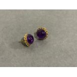 A pair of cabochon amethyst ear studs in 9ct gold, the circular stones collet set within twisted