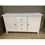 A white finish cabinet having three drawers to the centre flanked by an indented panel cupboard door