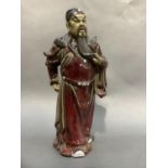 A deep red and black enamelled pottery figure of a Japanese male with long beard and flowing