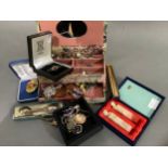 A fabric covered jewellery box containing a small collection of silver jewellery, silver golf spoons