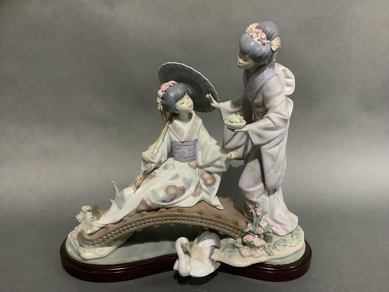 A large Lladro group of two Geishas, one sitting on a bridge with a parasol, the other standing