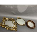 Three mirrors including a walnut oval with gilt slip, a gilt oval plaster frame, and a shield shaped