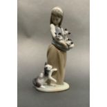 A Lladro figure of a girl holding kittens in her apron, a cat at her feet, 25cm high