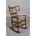 A 19TH CENTURY CHILD'S ELM AND RUSH SEATED ROCKING CHAIR with spindle turned back and wings,