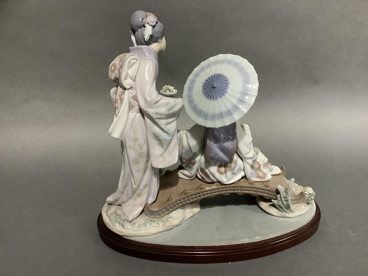 A large Lladro group of two Geishas, one sitting on a bridge with a parasol, the other standing - Image 2 of 2