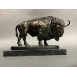 A bronzed figure of a buffalo on an oval textured base and marble plinth, approximately 24cm long by