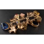 NINE CARAT GOLD CHARM BRACELET the charms including three swivel fobs, one with green and black