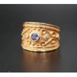 DIAMOND AND BLUE GEM SET RING the gemstones in wide scroll decorated fourteen carat gold band,