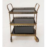 GILT METAL HOSTESS TROLLEY with three smoked glass shelves with pierced galleries and shaped