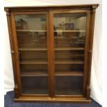OAK BOOKCASE with a moulded top above a pair of glass doors flanked by a pair of columns, the
