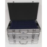 THREE ALUMINIUM COIN CASES two containing four removable trays and one with six trays, all with keys