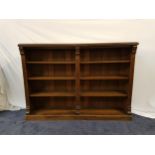 STAINED PINE BOOKCASE with a moulded top above four open front shelves, standing on a plinth base,