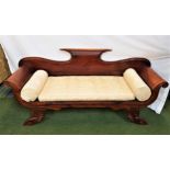 EMPIRE STYLE TEAK SOFA with a shaped back and scroll arms, standing on carved shaped supports,