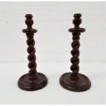 PAIR OF STAINED PINE BARLEY TWIST CANDLESTICKS raised on circular bases, 39cm high