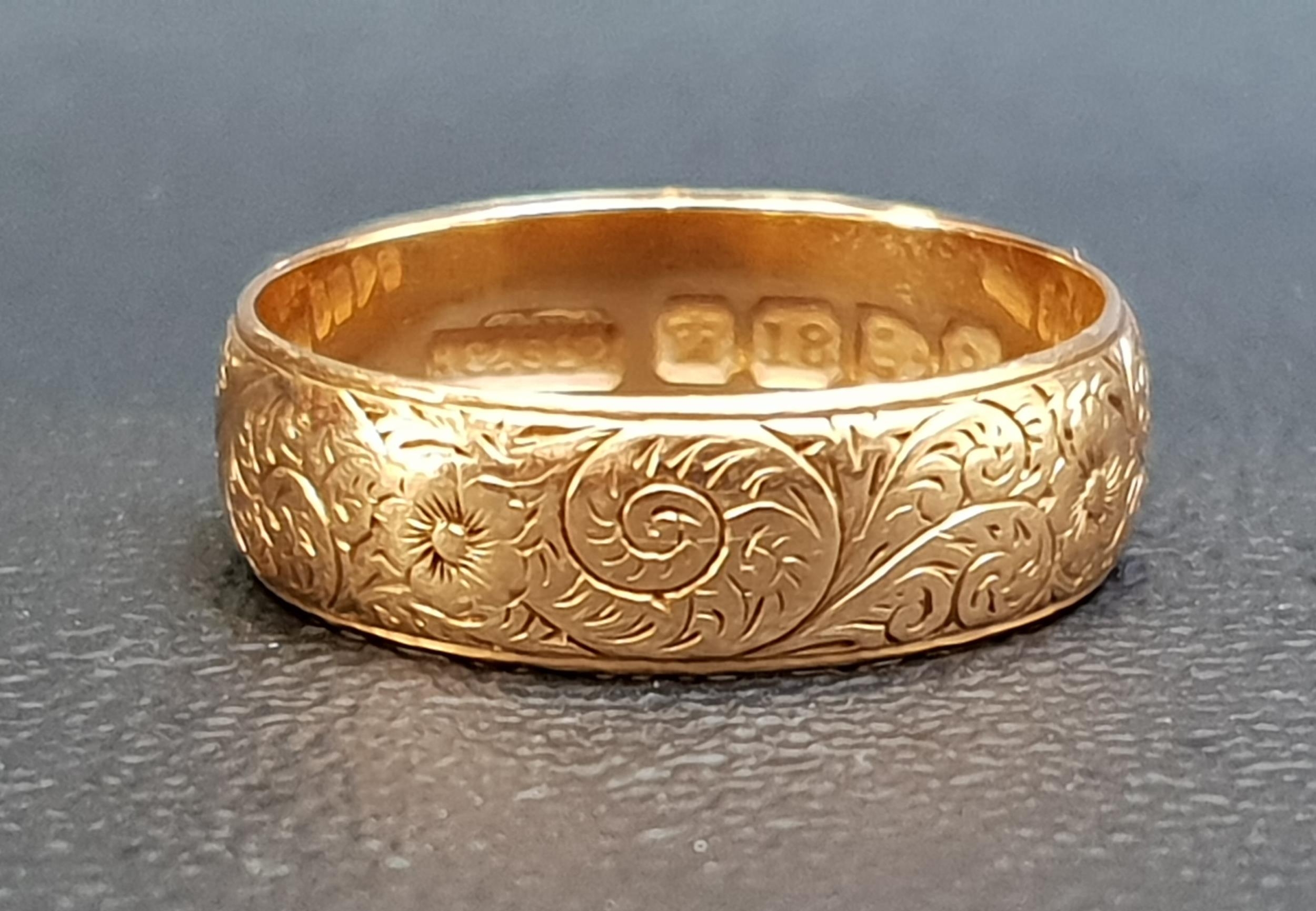 VICTORIAN EIGHTEEN CARAT GOLD WEDDING BAND with engraved scroll and floral decoration overall,