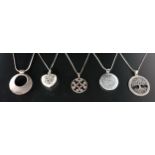 FIVE SILVER PENDANTS ON CHAINS including a pierced tree decorated example, a hammered circular